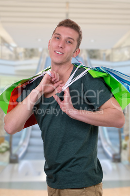 Junger Mann mit Einkaufstaschen in Shopping Mall