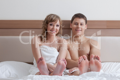 Happy attractive couple sitting in bed, close-up