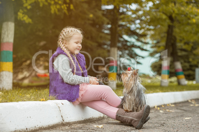 Image of cute little girl playing with dog in park