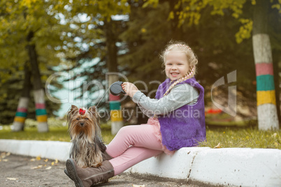 Smiling little blond girl posing with cute puppy