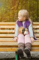Lovely little girl sitting on bench with her cavy