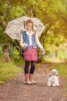Adorable little girl walking with dog in rain
