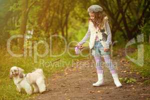 Cute curly-haired girl walking with dog in park