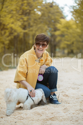 Smiling middle-aged woman playing with dog