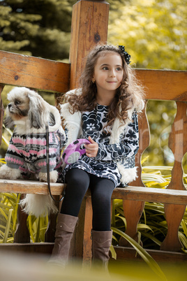 Cute brown-haired girl posing with puppy in gazebo
