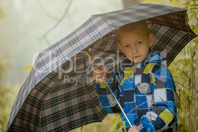 Pretty little boy posing under umbrella, close-up