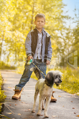 Smiling little boy walking with cute dog in park