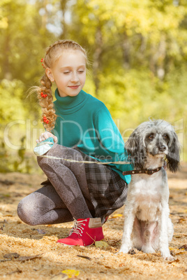 Lovely girl walking with dog in autumn park