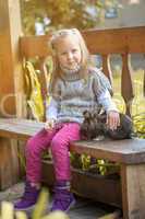 Pretty little girl sitting in gazebo with rabbit