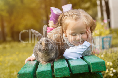 Adorable girl posing on bench with cute rabbit
