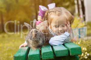 Adorable girl posing on bench with cute rabbit