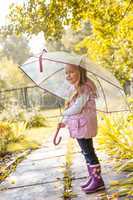 Slyly smiling girl posing under umbrella in park
