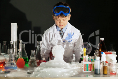 Adorable smart boy doing experiment in studio