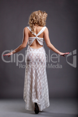 Slim girl in white negligee posing back to camera