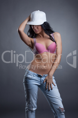 Portrait of sensual girl in cap, bra and jeans