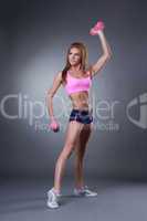 Muscular young woman exercising with dumbbells
