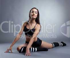 Graceful slender woman sitting on split in studio