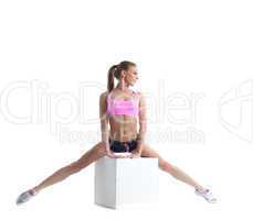 Pretty muscular athlete doing split on cube