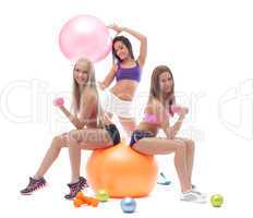 Smiling sporty girls posing with fitness items