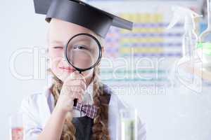 Smiling schoolgirl looks through magnifying glass