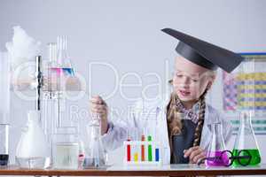 Cute schoolgirl works with chemicals in laboratory