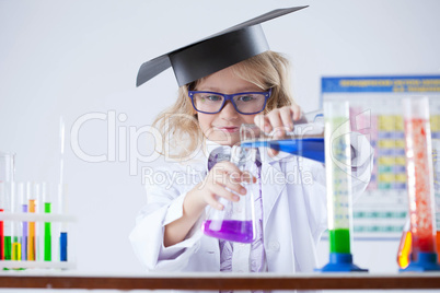 Curious schoolgirl pouring reagent into flask