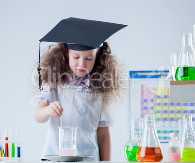 Cute curly-haired scientist stirs reagent in flask