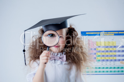 Focus on eye of little girl looking through loupe