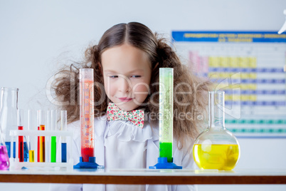 Slyly smiling girl posing with colorful test-tubes