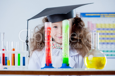 Funny little girl looks out of colorful flasks