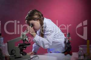 Diligent schoolgirl looking through microscope