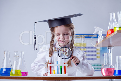 Little chemist looking at tube through magnifier