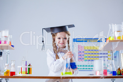 Smiling little girl posing in graduate hat at lab