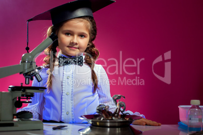 Cute girl posing in graduate hat, on pink backdrop