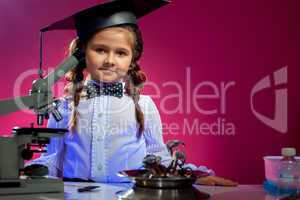 Cute girl posing in graduate hat, on pink backdrop