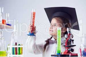 Smart little experimenter looking at test tube