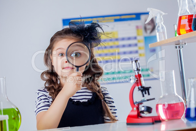 Cute dark-haired girl looking through magnifier