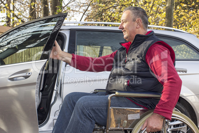 man in a wheelchair in the fall next to their car