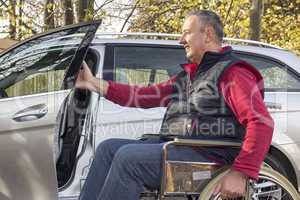 man in a wheelchair in the fall next to their car