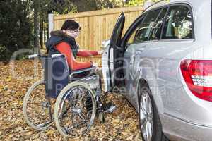 woman in a wheelchair in the fall next to their car