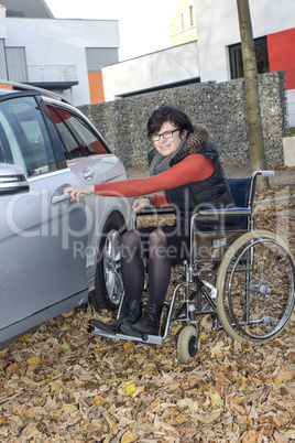 woman in a wheelchair in the fall next to their car