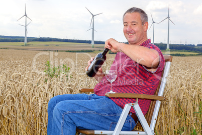 man sitting with wine bottle in cornfield
