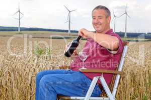 man sitting with wine bottle in cornfield