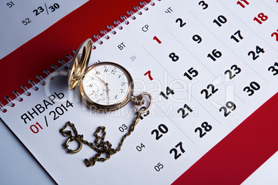 gold pocket watch and a wall calendar