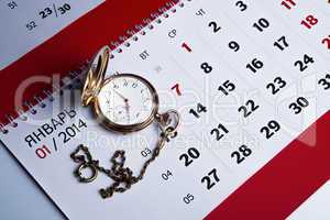 gold pocket watch and a wall calendar