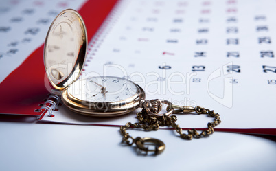 gold pocket watch and a wall calendar