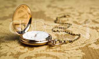 gold pocket watch on gold tablecloth