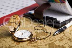 gold pocket watch and a wall calendar and sketchpad