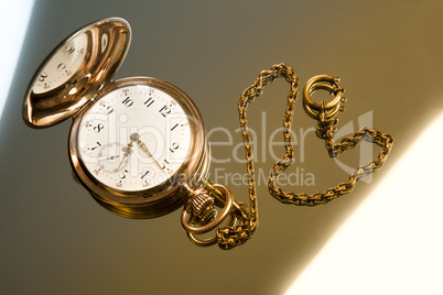 gold pocket watch on gold glass background
