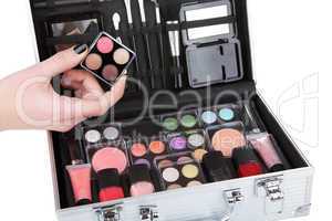 Opened aluminum make up case and female hand holding an eyeshado